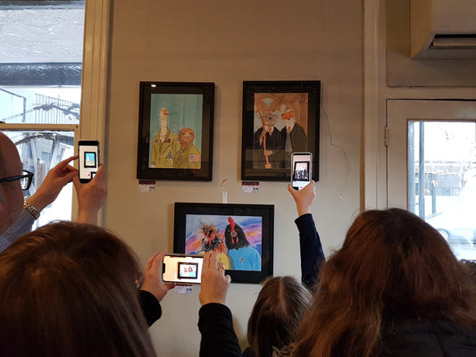 Three people scanning three artworks with the Artivive app to experience the augmented reality.
